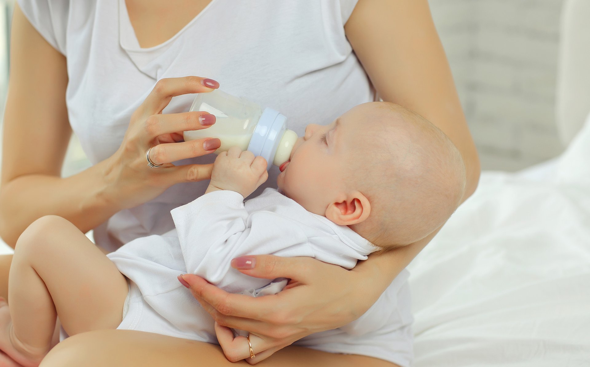 Kobieta daje dziecku butelke z mlekiem modyfikowanym do picia