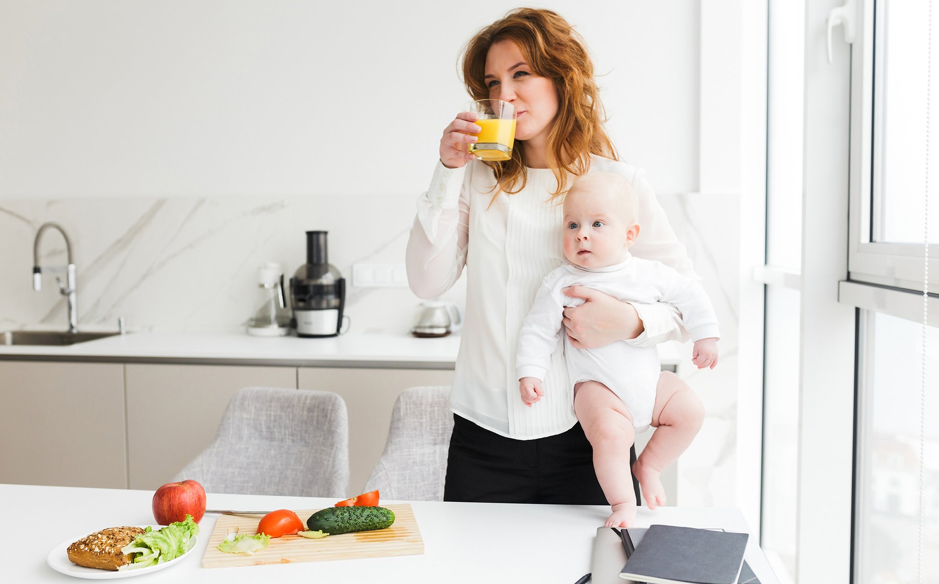 Kobieta pije sok pomaranczowy trzymajac dziecko