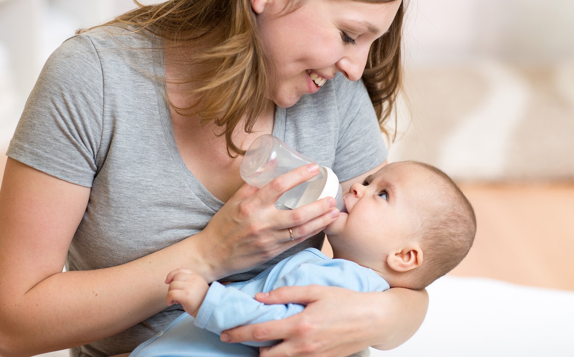 Kobieta karmi dziecko butelka z mlekiem usmiechajac sie