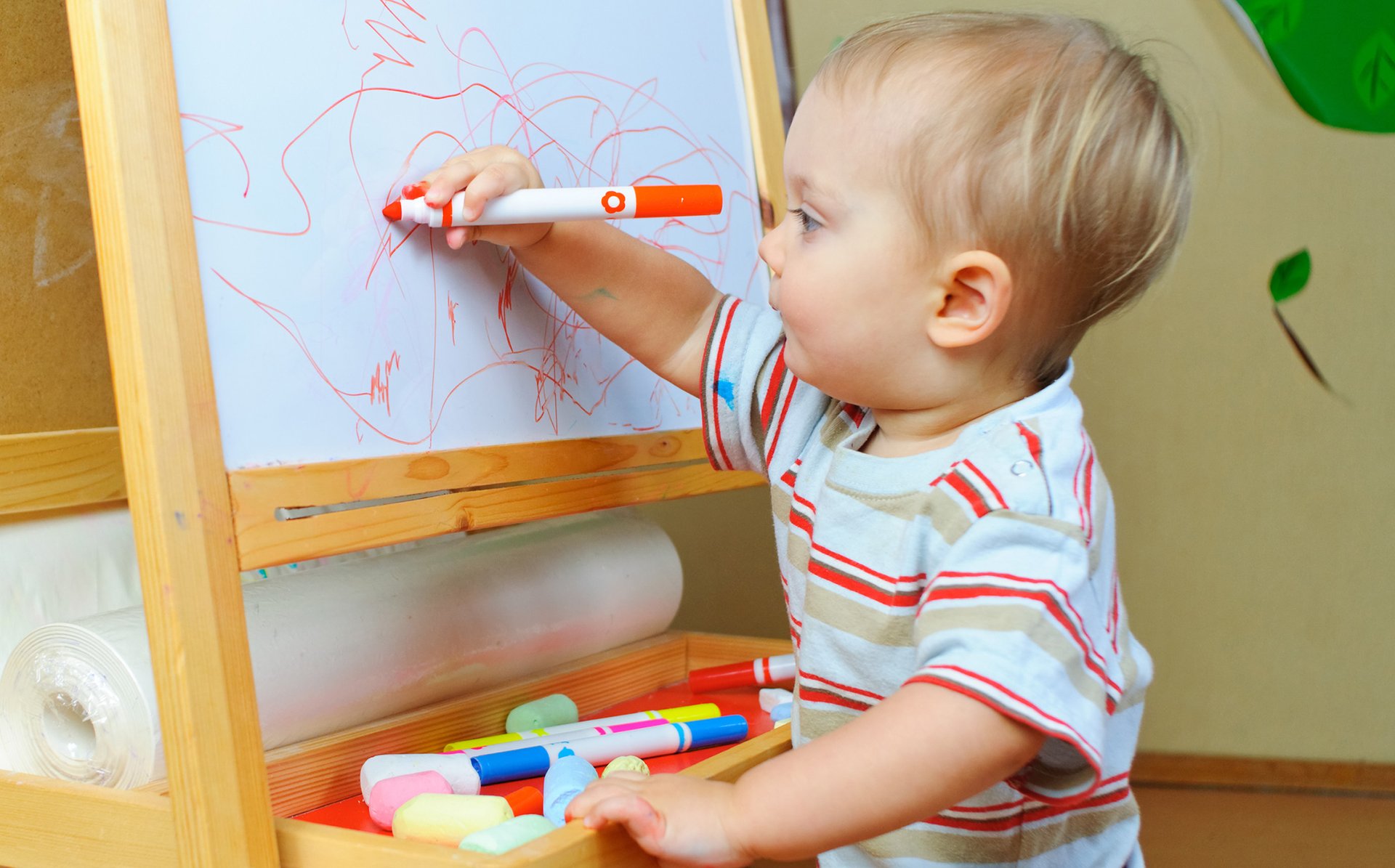 Dziecko rysuje mazakiem szlaczki po tablicy