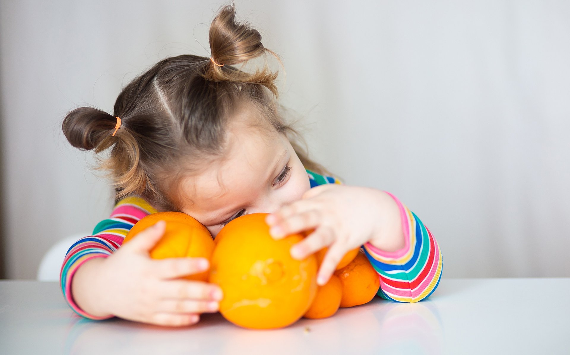 Dziecko trzyma w objeciach kilka pomaranczy