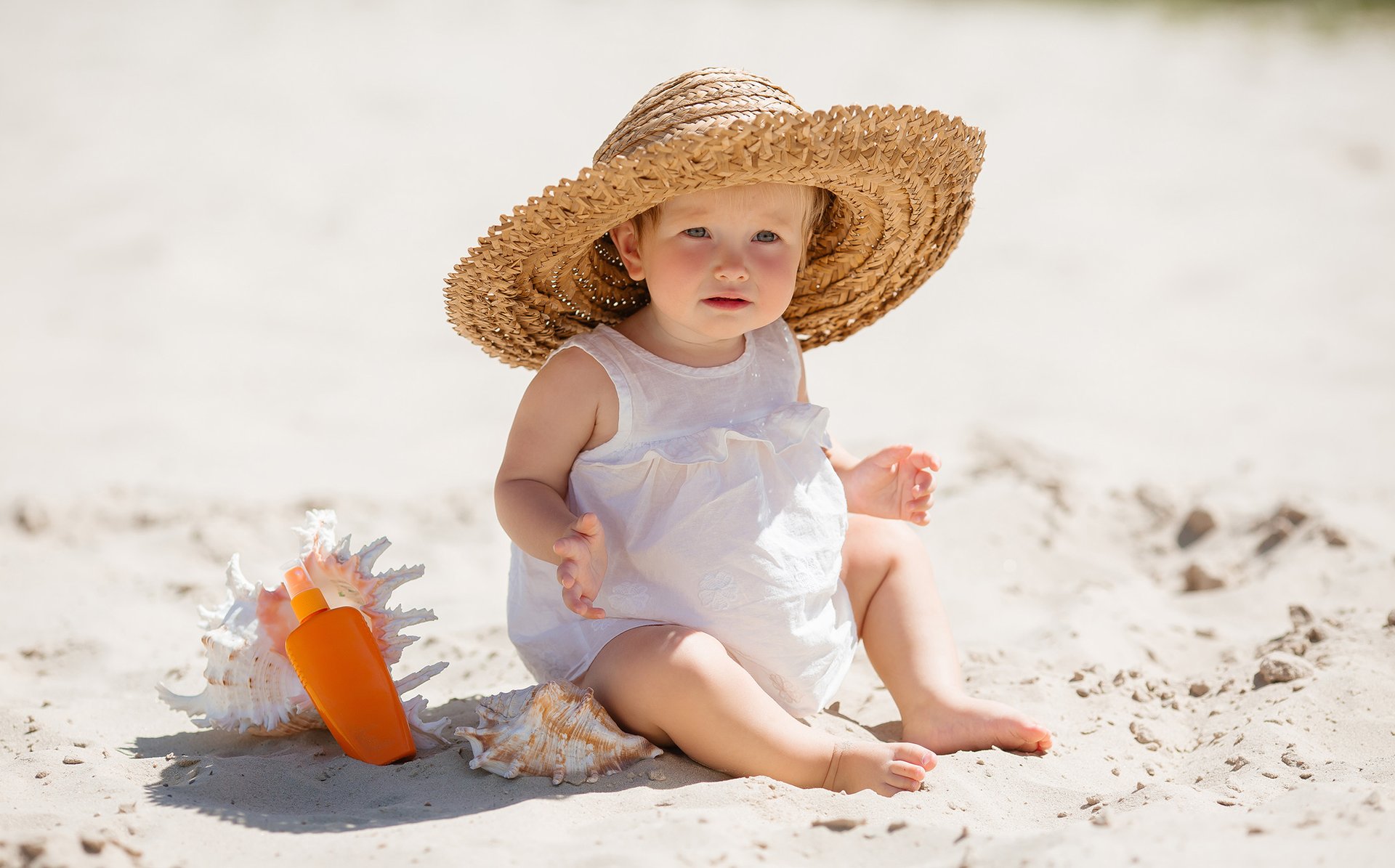 Dziecko w kapeluszu siedzi na plaży